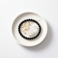 Black Obsidian bracelet flat lay on ceramic tray with crystals and dried flowers — editorial product photography