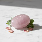 Rose Quartz Palm Stone with soft pink color on marble surface