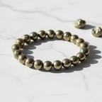 Pyrite Crystal Bracelet with golden metallic fool's gold beads on marble surface
