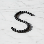 Lava Crystal Bracelet with black porous volcanic stone beads on marble surface