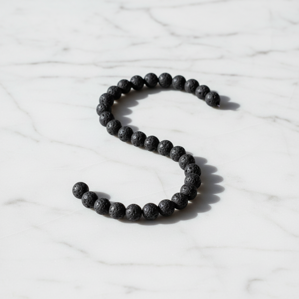 Lava Crystal Bracelet with black porous volcanic stone beads on marble surface