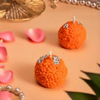 Close-up of handmade orange Laddu candles with textured finish and visible wicks