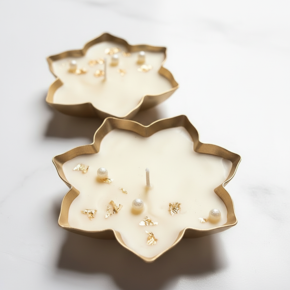 Hero shot of gold leaf lotus-shaped urli candle with pearl beads and gold foil flakes on ivory soy wax, premium spa-luxury product photography by Just Natural Purity