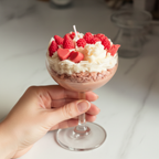 Elegant hand holding strawberry sundae candle in coupe glass, soft natural light