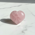 Rose Quartz Heart Stone with soft pink color on marble surface