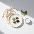 Abundance & Growth Crystal Set - Green Aventurine, Tiger Eye, Amethyst and Bronzite tumbles on white plate with cotton potli