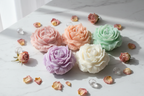 Rose bloom candles in multiple pastel colours group shot on white marble - Just Natural Purity