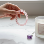 Sister's Love Crystal Gift Set - elegant hand holding Rose Quartz bracelet with candle and pendant on white marble
