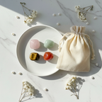 Rare & Precious Crystal Set - top-down flat lay of Rose Quartz, Green Aventurine, Tiger Eye and Red Carnelian tumbles with cotton potli