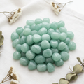 Light green Aventurine tumble stones bunch flat lay on white linen with botanicals